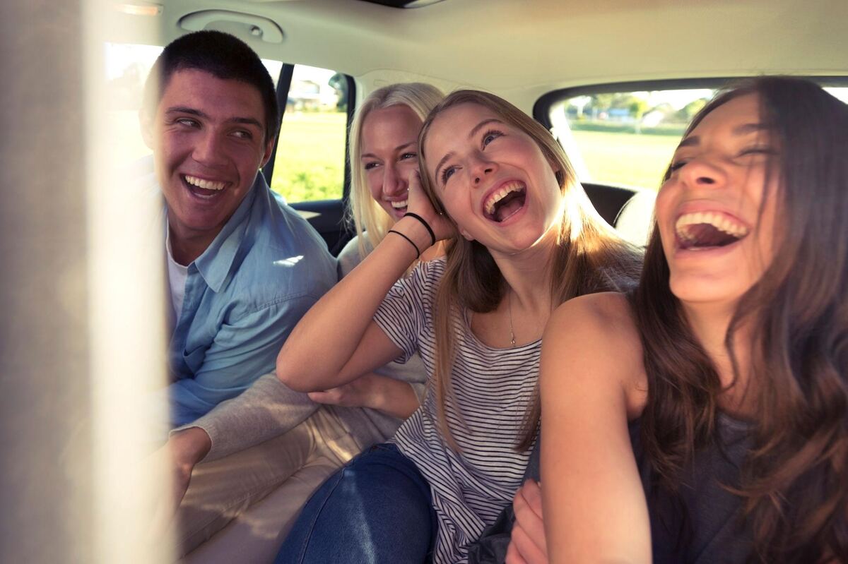 Four friends in the back of a car lit by low golden sun