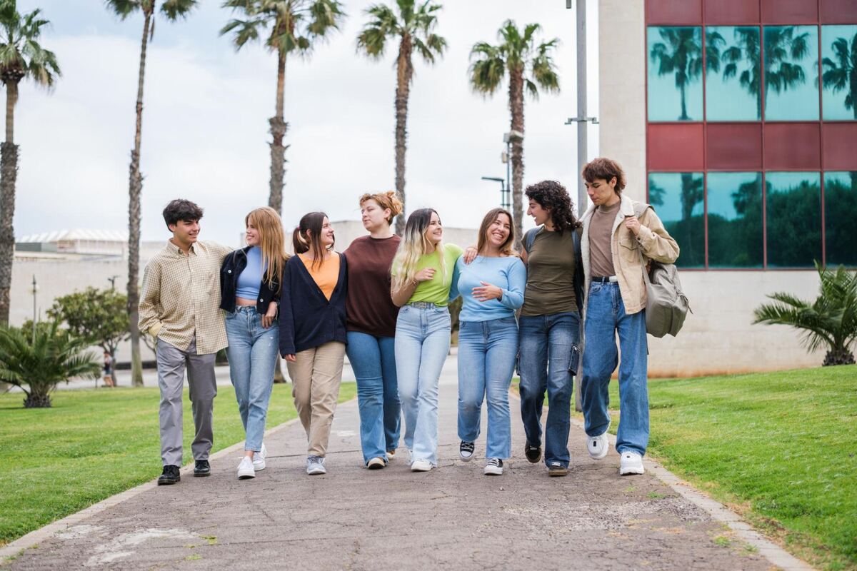 A group of students walking arm in arm down a campus walkway