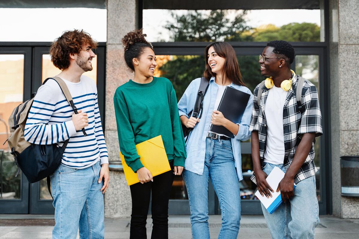 Students standing with course folders outside a university building after class