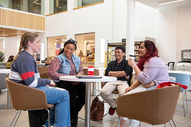 People talking around a small table in a bright campus cafe